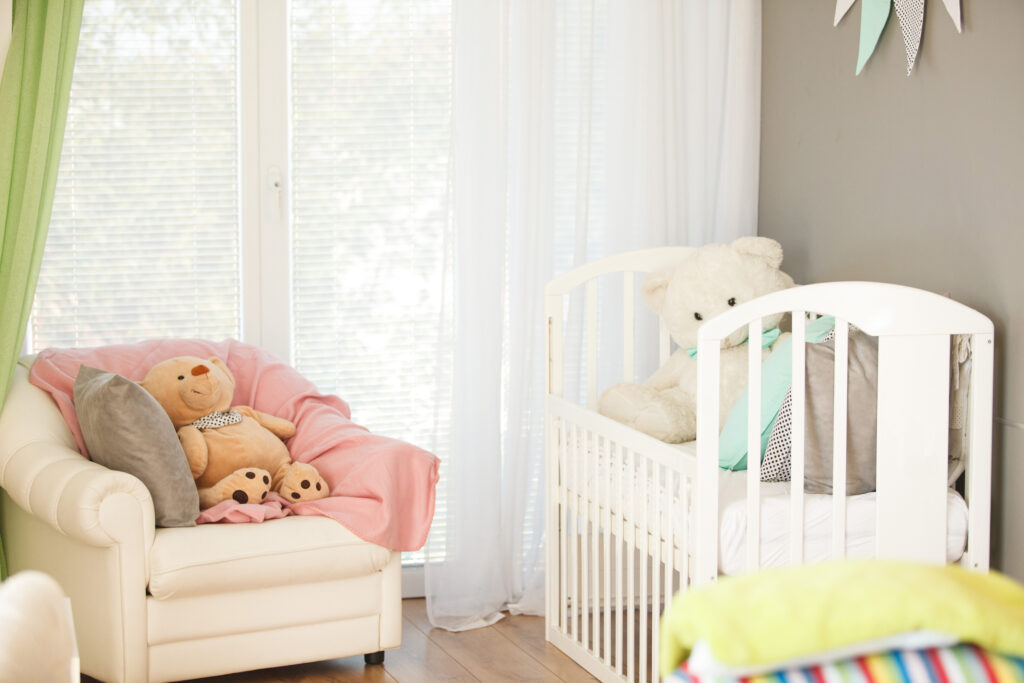 Shot of pastel colored nursery bedroom with white crib, armchair, and children toys.