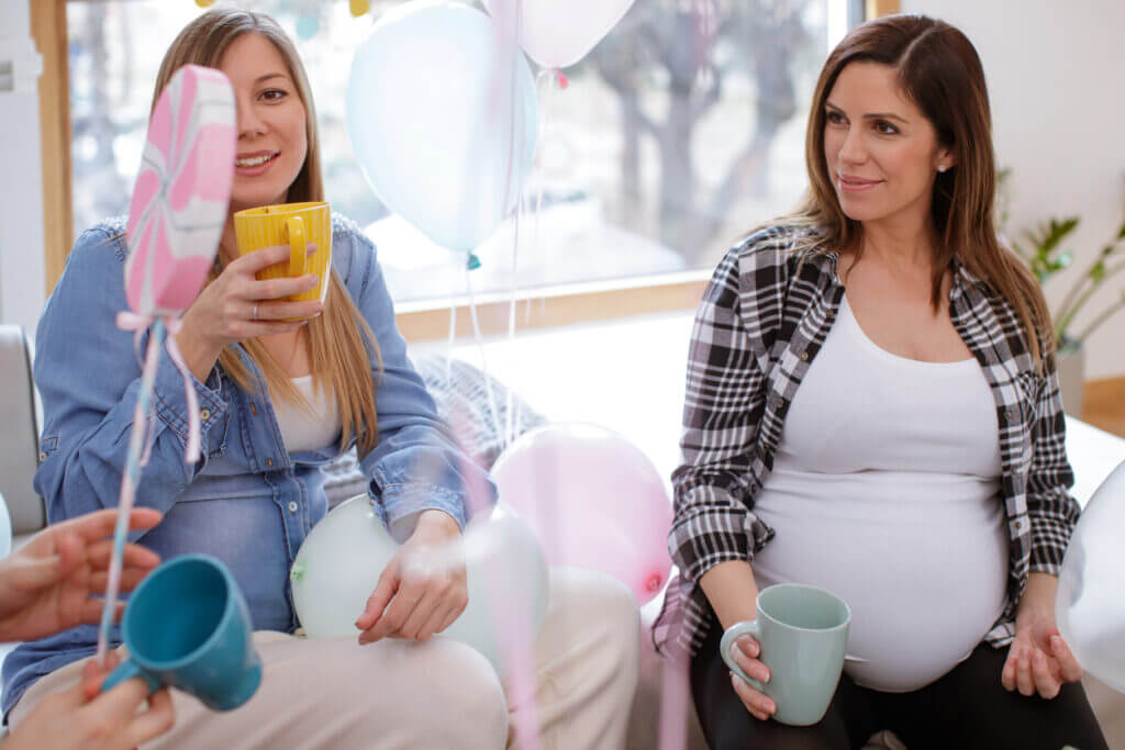Pregnant women sitting in living room, having tea and talking