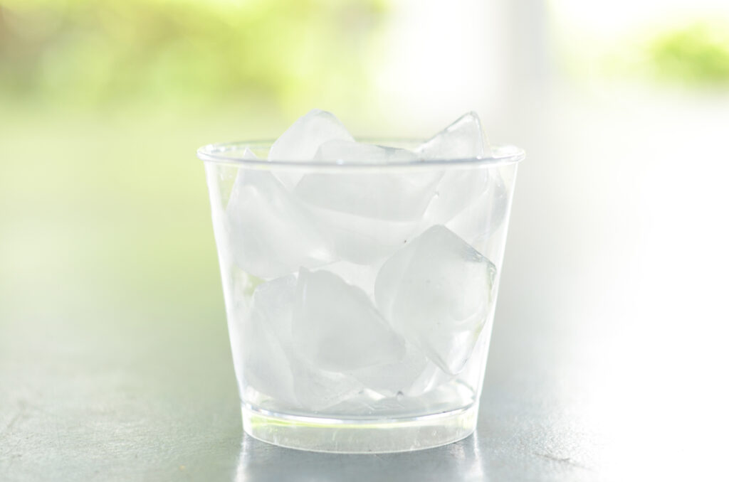 Water with crushed ice cubes in glass on blurred beautiful background