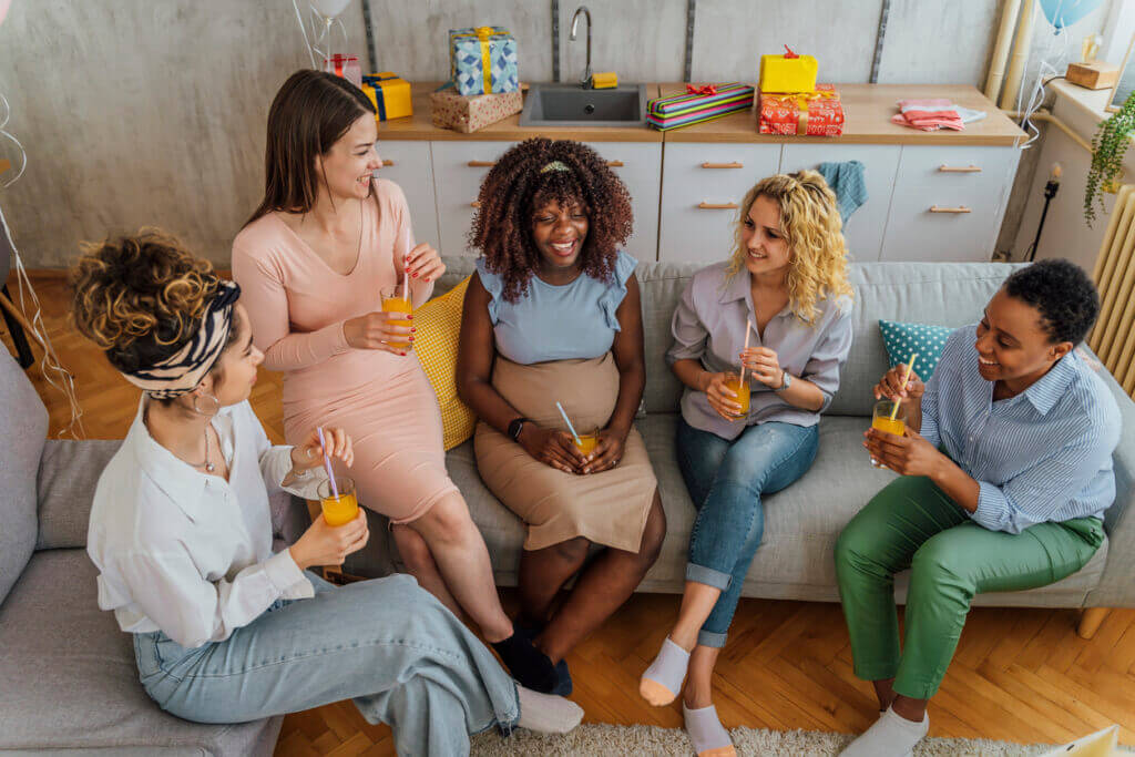 Group of diverse women together at baby shower. Smiling young pregnant black woman celebrating baby shower with best friends