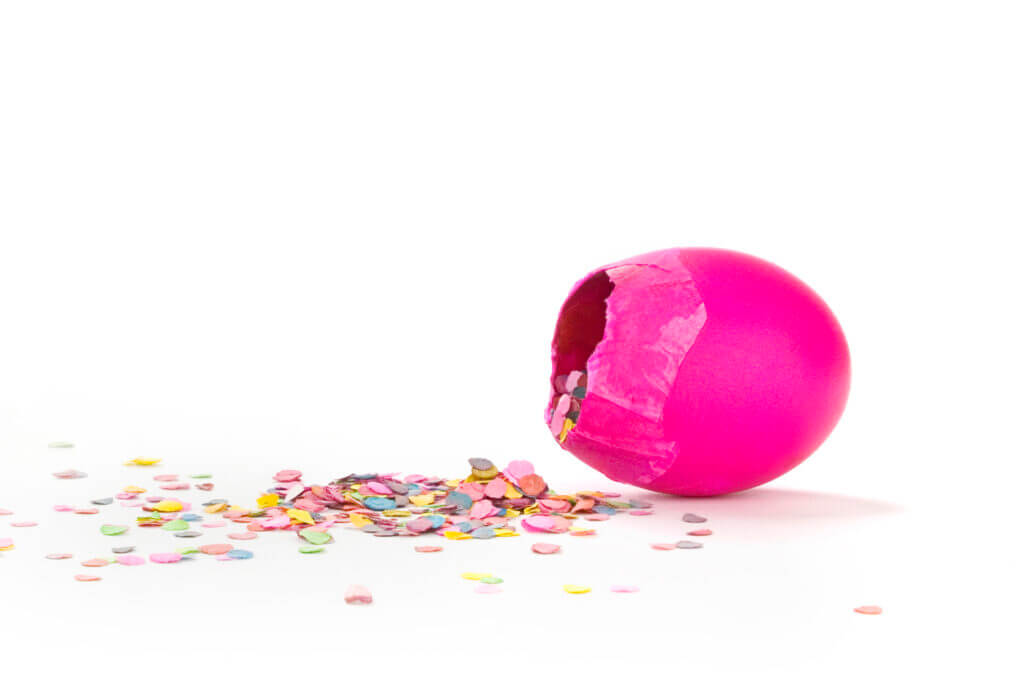 A Pink Cascarone filled with confetti against a white background.