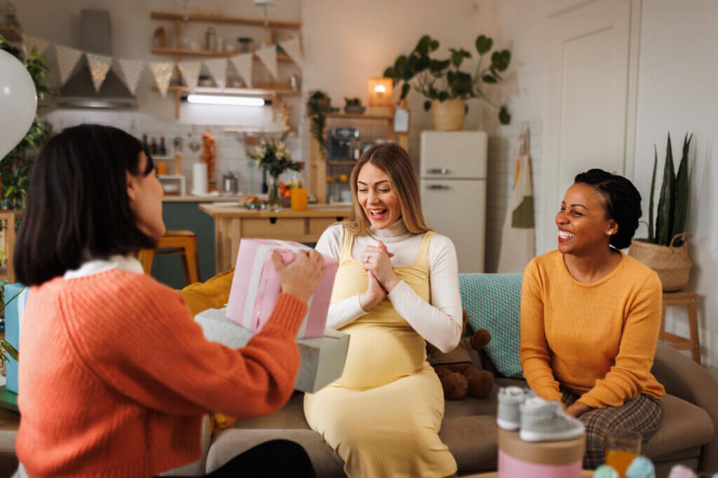 Young beautiful pregnant woman getting presents on a baby shower party at her apartment