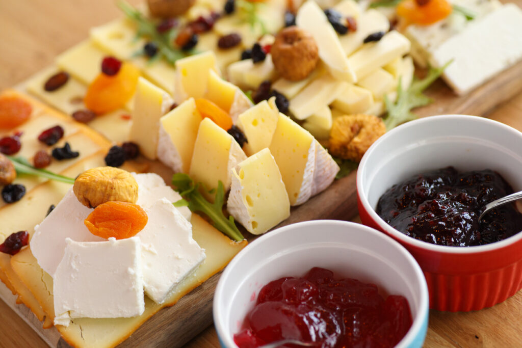 Cheese board with various types cheese, dried fruit and jam. Close-up.
