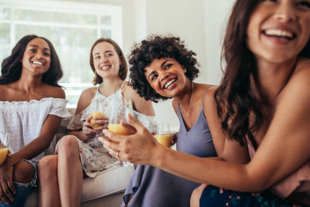 Group of multiracial friends at a party and smiling. Women friends having a party at home and looking away.
