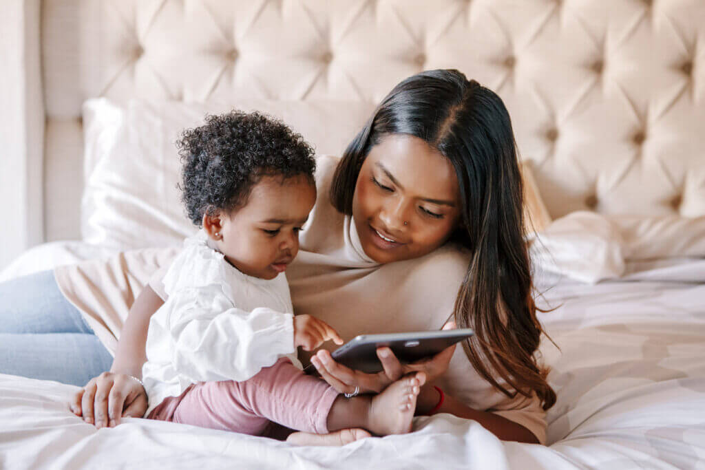 Mixed race Indian black mother with toddler baby girl watching cartoons on tablet. Ethnic diversity. Family mom with kid using technology. Video chat, video call. Black people community.