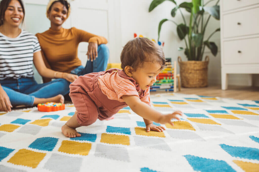 Young mothers playing with baby girl in living room.