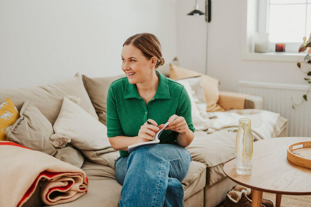 Woman indoors at home relaxing on sofa with her analog notebook