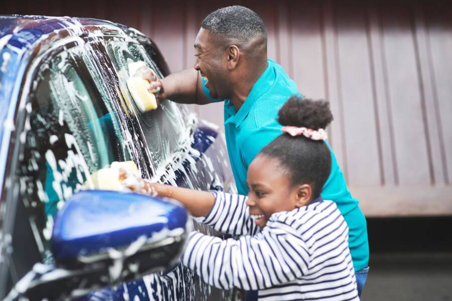 father and daugther washing car while having fun