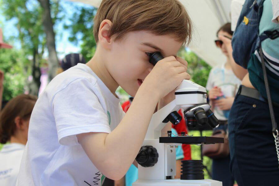 young kid loking into microscope