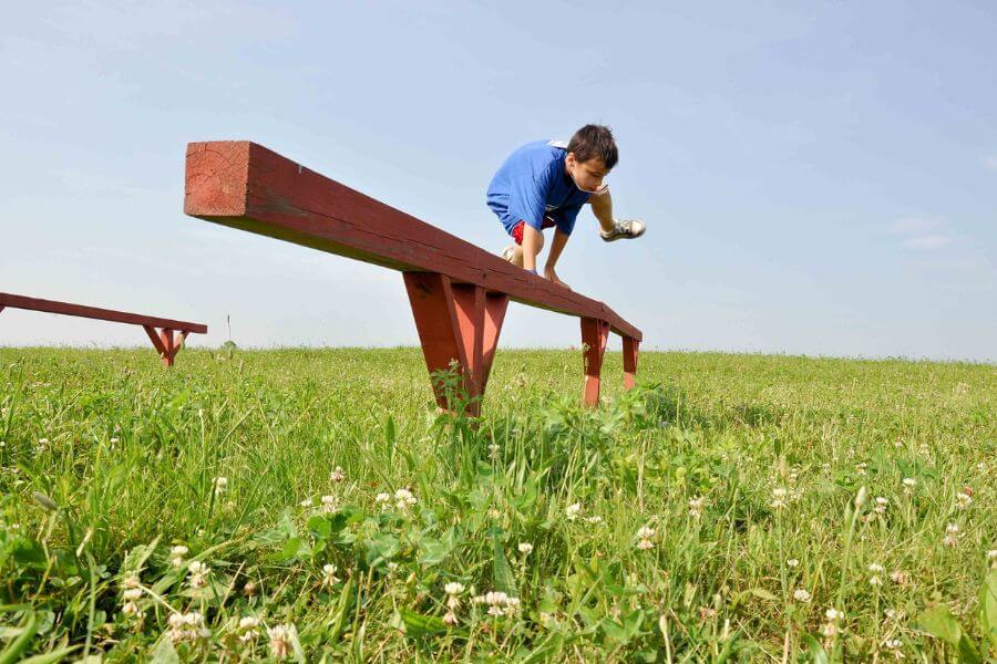 little boy jumping over a fence